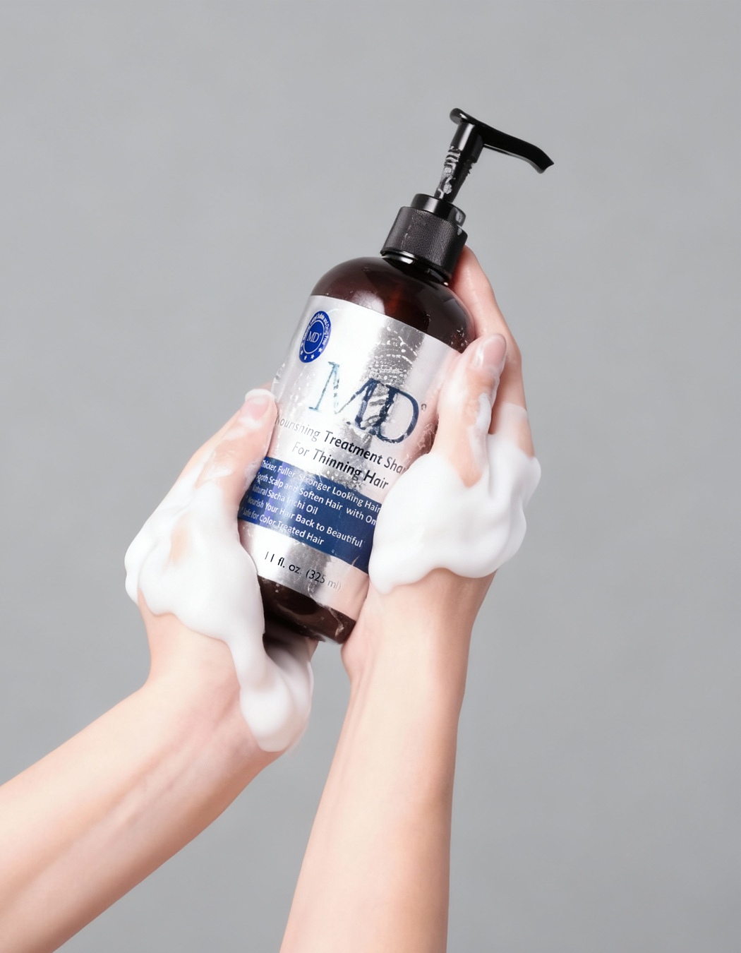 Hand holding the MD Revitalizing Treatment Shampoo bottle in the shower