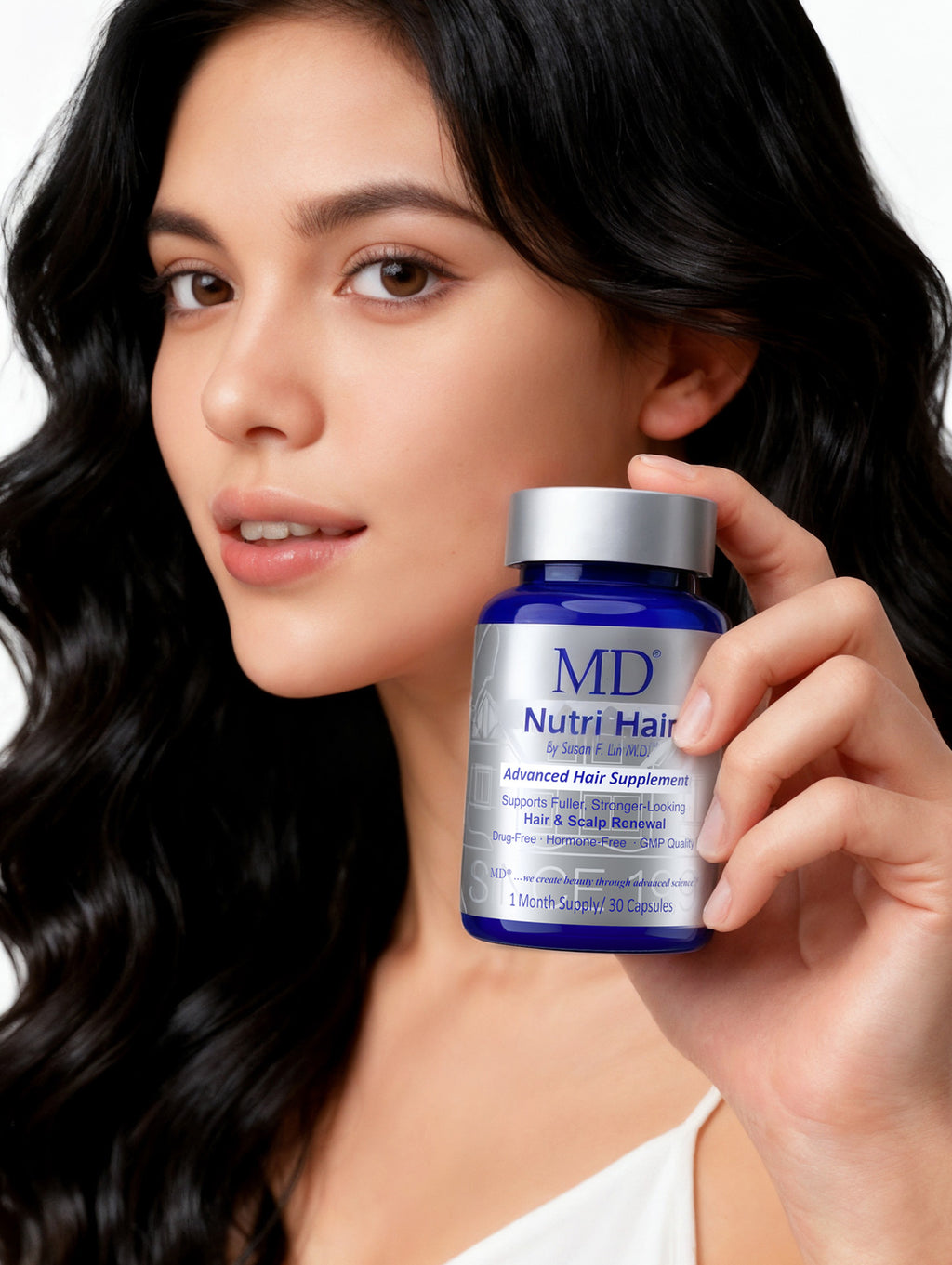 A woman with long dark wavy hair holds a blue bottle of MD Nutri Hair Advanced Hair Supplement against a clean white background.